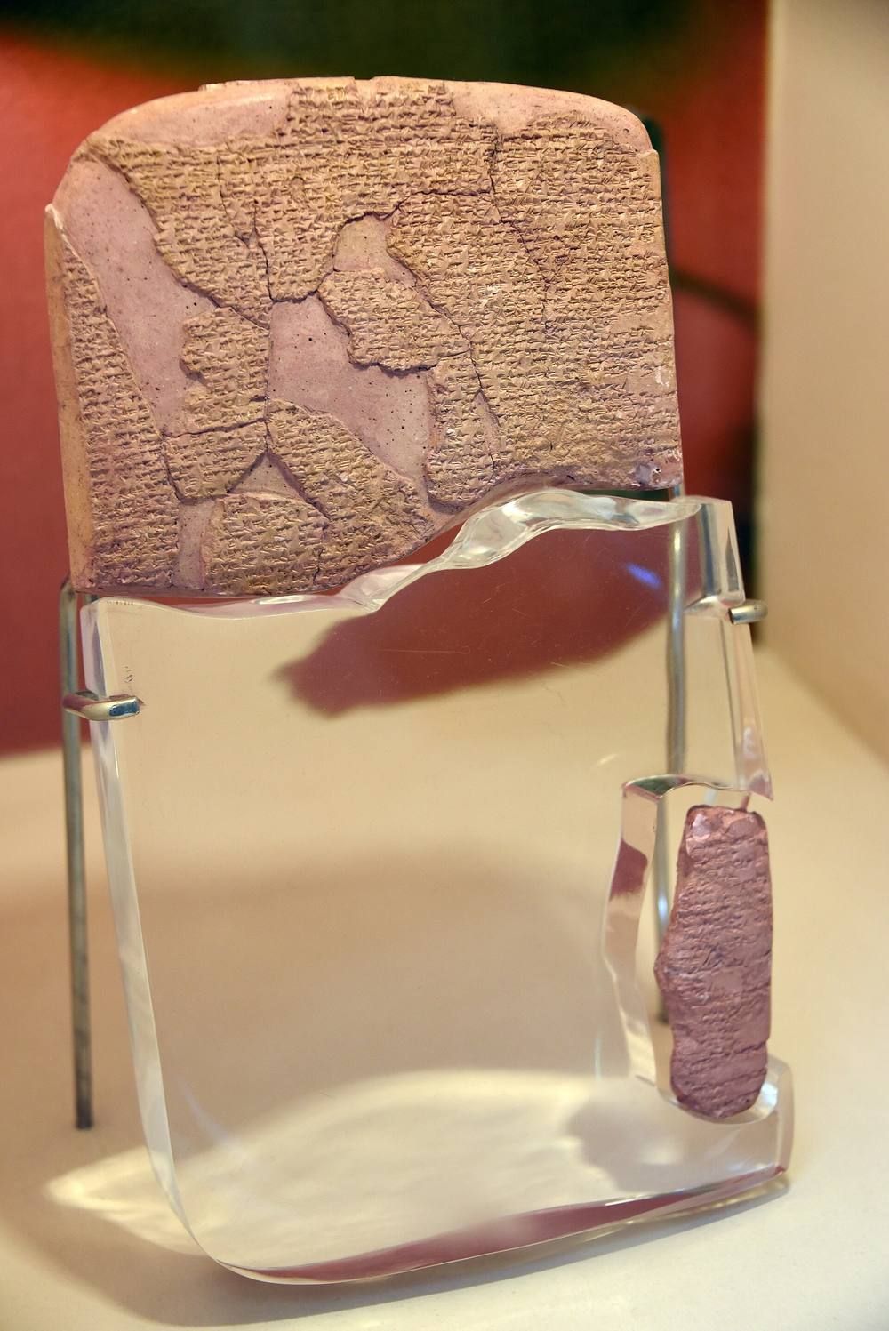 A clay tablet covered in cuneiform in a museum case.